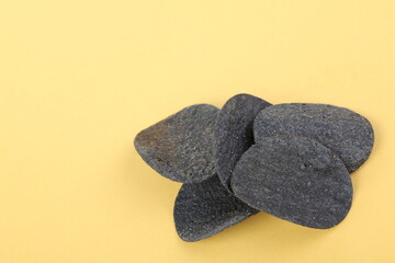 Black potato chips on yellow background. Texture and background. Close up.