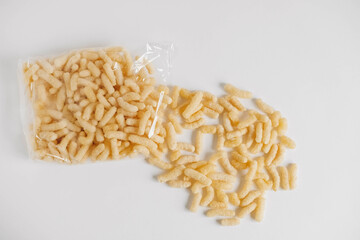 Corn sticks in a plastic bag scattered on a white background. Top view. Copy, empty space for text