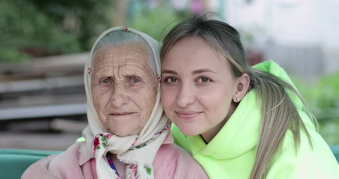 Portrait of an old woman with deep wrinkles together with a young girl. A cute grandmother with her granddaughter are smiling.