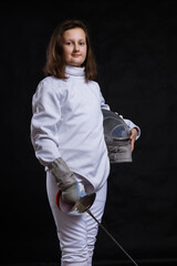 Teenage girl fencer dressed in uniform with epee and helmet