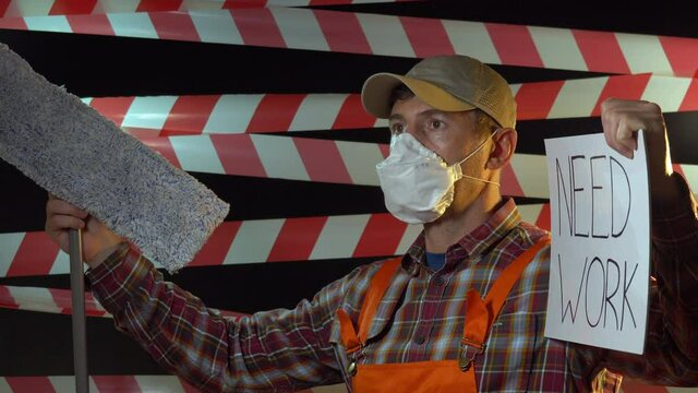Portrait of male office cleaner with a poster need work. Unemployed man on the background of barrier tape. Labor market changes after COVID-19 coronavirus affect key workers. Worker in face mask