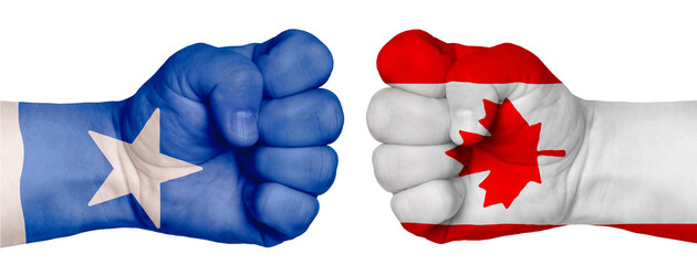 Two hands are clenched into fists and are located opposite each other. Hands painted in the colors of the flags of the countries. Canada vs Somalia