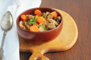 Meat stew with vegetable and mushrooms in bowl on rustic wooden background