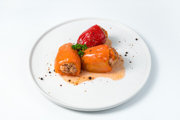 Three red and orange Bulgarian peppercorns with meat on a white plate. Culinary background, side view. The concept of cooking.