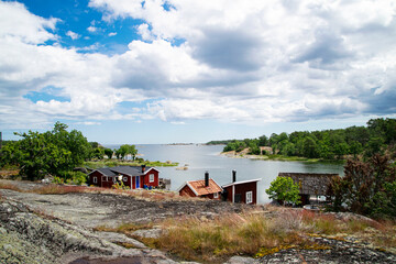 Beautiful summer day in the archipelago. A very picturesque view with red summer holiday houses next to the sea on the island. Photo taken in Sweden.