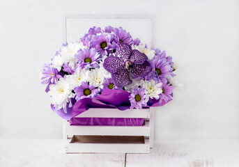 Beautiful bouquet with lilac orchid and white, purple chrysanthemums in a wooden basket....