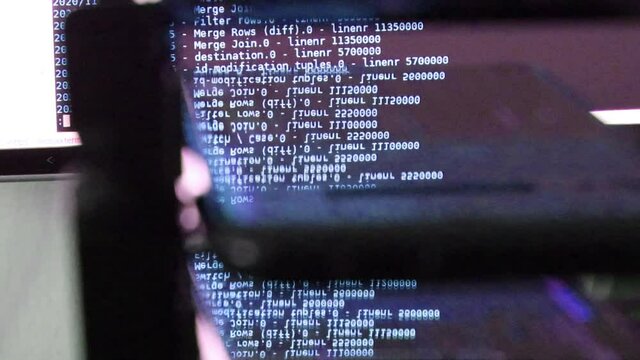 blue computer software code moving on a black monitor reflect on glass. Abstract computer hacking in process with rack server base, dynamic text running and flowing on pc screen