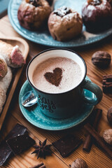 turquoise cup of hot coffee on grey background with cinnamon sticks and christmas decorations