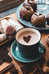 turquoise cup of hot coffee on grey background with cinnamon sticks and christmas decorations
