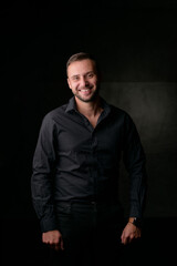 Obraz premium Studio portrait of a young caucasian man in a black blazer, looking at the camera, standing against plain studio background