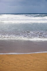 Waves on the coast reaching to the sand in the beach