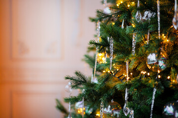 bright garland of yellow light bulbs. background or texture for a holiday greeting card. Christmas tree in the apartment. green branches of Christmas decorations balls.