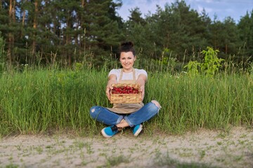 Fototapeta premium Mid adult woman with basket of fresh strawberries in countryside