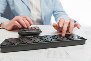 Business woman using calculator and computer keyboard