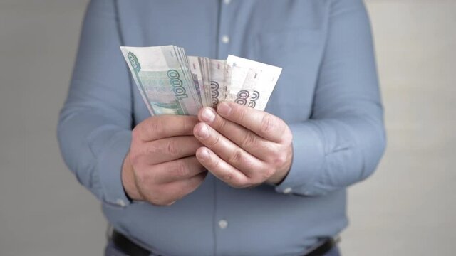 man holding in hands a fan of russian rubles close-up
