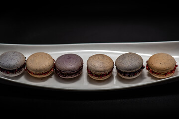 Set of delicious macaroons expensive candies on the black background