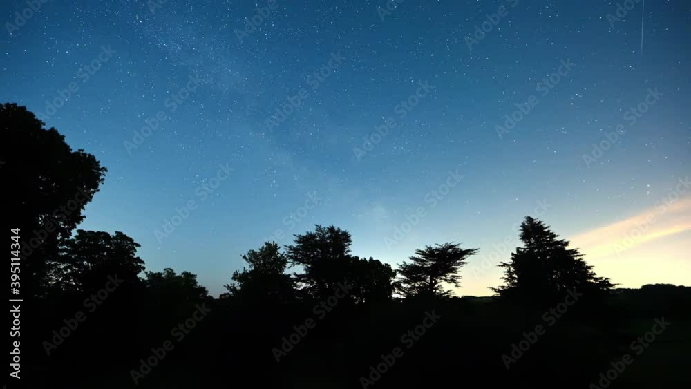 Wall mural timelapse of a push through a silhouette window to reveal stars in a clear night sky and dark trees 