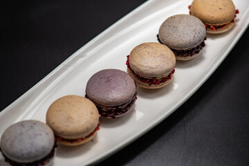 Set of delicious macaroons expensive candies on the black background