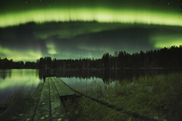 Northern lights on the lake. Reflection in water.