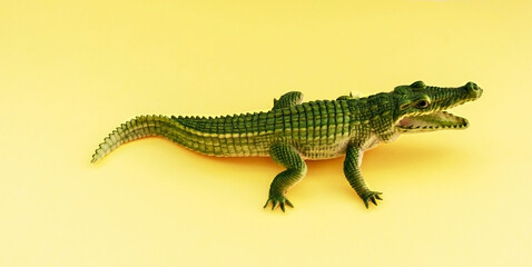 Childrens rubber toy of green crocodile alligator with open mouth on yellow background