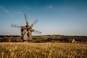 Fototapeta na wymiar old wooden windmills stand in a field near the forest 1