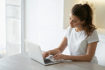 A woman is engaged in online shopping in the website app on a laptop computer gadget, shopping home for food products from a store near her home. Copy space