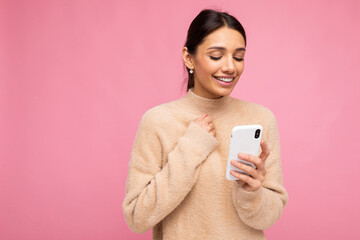 Young woman over isolated pink background sending a message with the mobile