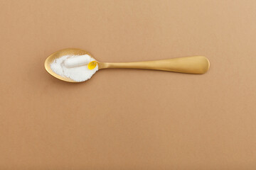 Collagen powder and pills on golden spoon. Extra protein intake. Natural beauty and health supplement for skin, bones, joints and gut. Flat lay, top view, copy space