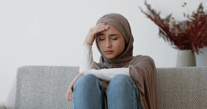 Seasonal depression. Young sad muslim woman suffering from mood swings, thinking about life problems, sitting at home