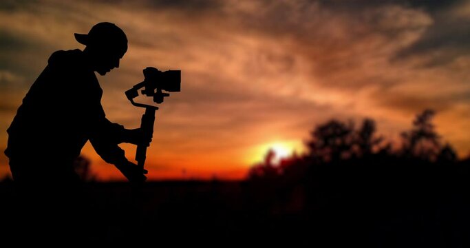 Time lapse: Silhouette of videographer is filming with cinema gimbal video dslr at sunset , professional video, videographer in events. Cinema lens on gimbal. Medium shot from right side