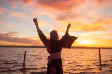 silhouette of a girl wearing a traditional japanese kimono with a vibrant sunset in the background