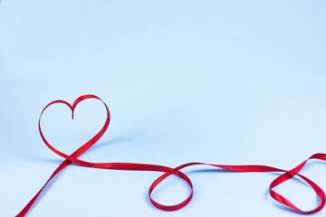 The concept of minimalist Valentine's day heart with ribbon on a blue background copy space