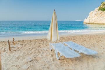 Two beach chairs and umbrella on the beautiful sand beach waiting for someone to come relax. Travel, holidays and resort concept.