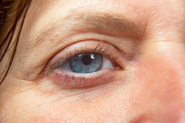 Closeup of the left blue eye, caucasian middle aged woman