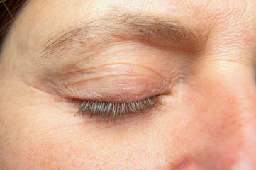 Naklejka premium Detail of a right closed eye of a woman. Front view. Details of a male face, closeup.