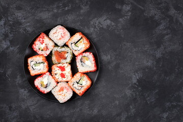 Fresh sushi rolls with sauce on dark, traditional japanese cuisine, place for text, top view, banner for shop advertisement or invitation, selective focus