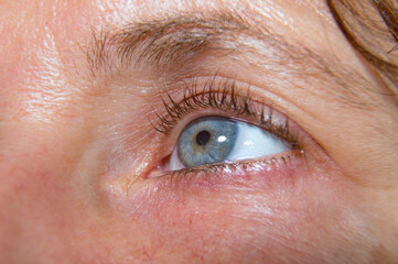 Close-up shot on a beautiful feminine blue eye in profile
