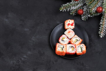 Herringbone made from fresh sushi rolls with sauce on dark, christmas new year food, traditional japanese cuisine, place for text, top view, banner for shop advertisement or invitation
