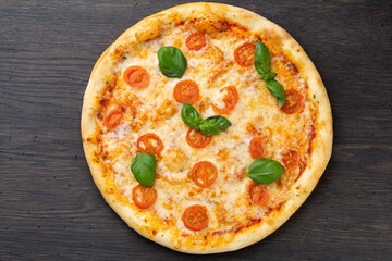 Italian pizza with melted mozzarella cheese, olives and sausage garnished with fresh vegetables and basil leaves
