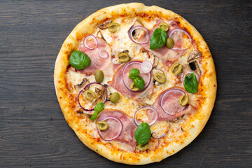 Italian pizza with melted mozzarella cheese, olives and sausage garnished with fresh vegetables and basil leaves