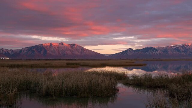Colorful sunset over the marsh of Utah Lake reflecting the snow capped mountains in vibrant hues.