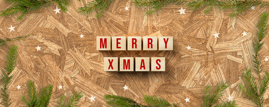 cubes with message MERRY XMAS and christmas decoration on wooden background