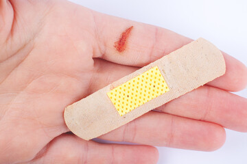 Wound on the finger and a plaster in the hand close-up. Health concept.