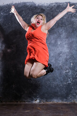 Fototapeta na wymiar Attractive plump woman in red dress jumping