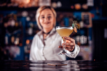 Girl barman formulates a cocktail in the bar