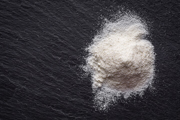 granulated milk powder on a dark stone background