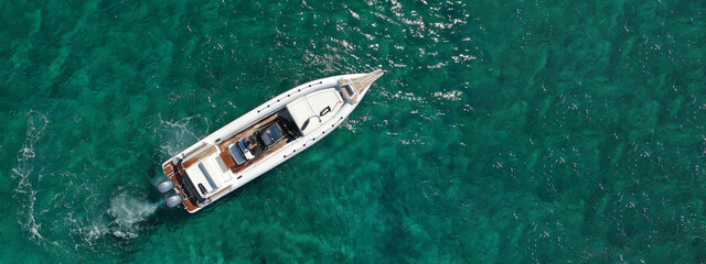 Aerial drone ultra wide panoramic photo of luxury inflatable rib cruising in low speed in tropical exotic bay with emerald sea