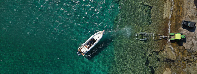 Aerial drone ultra wide top view photo of speed boat on trailer being towed by truck from emerald exotic sea to land