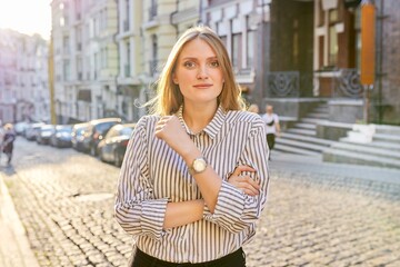 Urban portrait of beautiful young blonde woman on city street at sunset