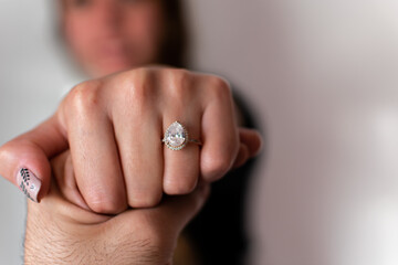 A woman's hand showing her engagement ring on a blurry background.  A wedding ring on hand